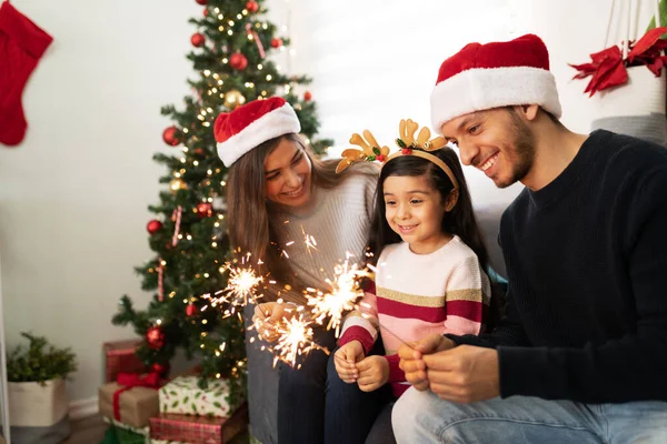小さな女の子はクリスマスに非常に感銘を見ている間自宅で輝きを使用してヒスパニック系の家族の肖像画 — ストック写真