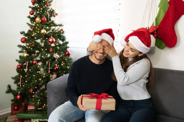 美しいブルネット女性カバー男の目に彼に驚きを与えながらクリスマスプレゼントに家 — ストック写真