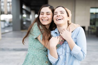 Çok ırklı, çekici lezbiyen çift arkadan gülüyor ve sarılıyorlar. 