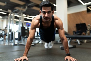 Kollarını ve karnını spor salonunda güçlendirmek için egzersiz yapan güçlü bir İspanyol gencin portresi.