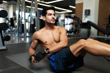 Kaslı İspanyol genç adam spor salonunun zemininde karın bölgesi için egzersiz yapıyor.