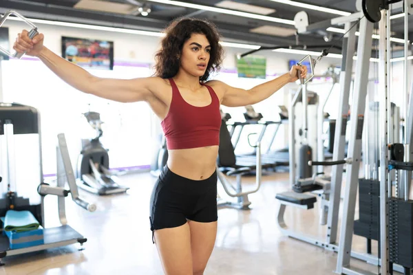 拉丁美洲的年轻女子用缆绳机伸展胳膊 在体育馆里锻炼胸部肌肉 — 图库照片