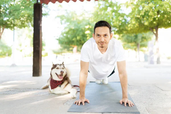 魅力的な大人ヒスパニック男行使上のマットとともに彼の安らかな犬でザ公園 — ストック写真
