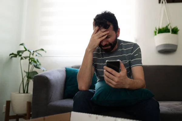 Hombre Latino Llorando Sentado Sofá Mientras Mira Mensaje Texto Celular —  Fotos de Stock