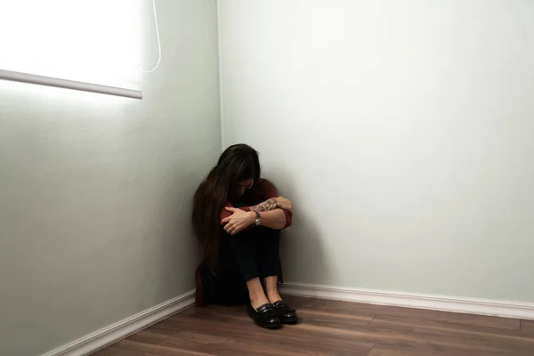 うつ病や孤独を患っている若い女性は 家の隅に座っている 膝の間に顔を隠すラテン女性 — ストック写真
