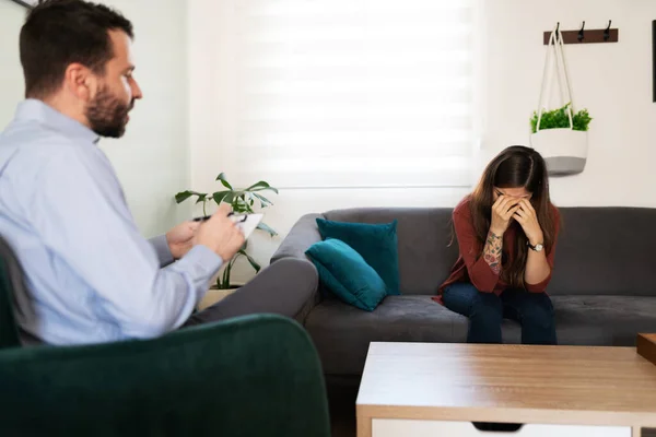 在与男性精神病医生的治疗过程中 20多岁的西班牙裔女性哭着捂住了脸 — 图库照片