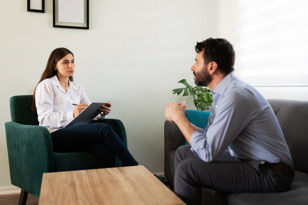 Побочный обзор взрослого мужчины, обсуждающего свои психологические проблемы с психиатром-женщиной во время сеанса терапии