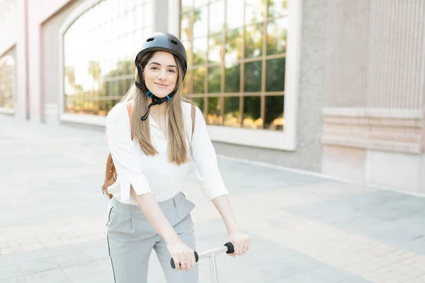 三十多岁的快乐女工骑着环保的摩托车和头盔在一座城市的建筑物外工作 — 图库照片
