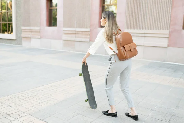 三十多岁的金发女工准备乘滑板到城里去工作 — 图库照片