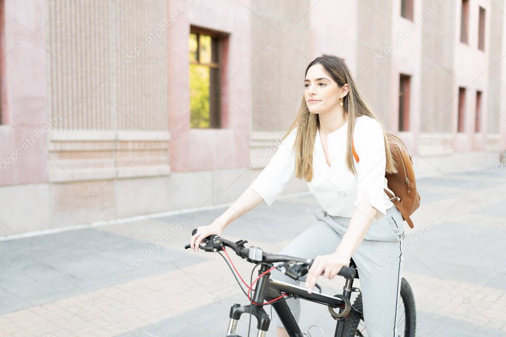 Pretty woman in her 30s with an active lifestyle riding a bike in her commute from home to her office building