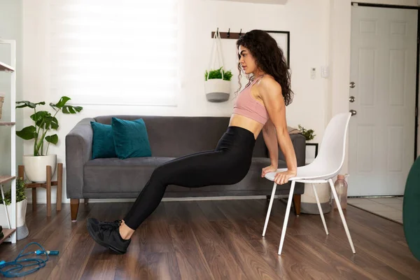 매력적 여자가 집에서 운동을 여자가 거실에 의자를 사용하여 테이프 소리를 — 스톡 사진