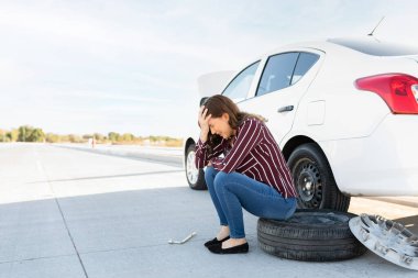 Üzgün genç bir kadın yolun kenarında oturup ağlıyor çünkü lastiği patlamamış. 