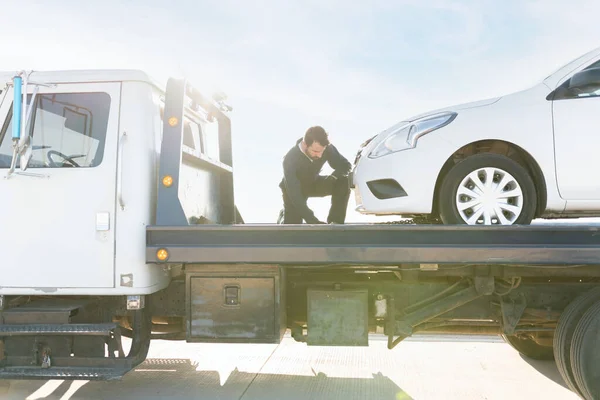 車両が牽引トラックプラットフォーム上で安全かつ適切に配置されていることを確認する男性オペレーター — ストック写真