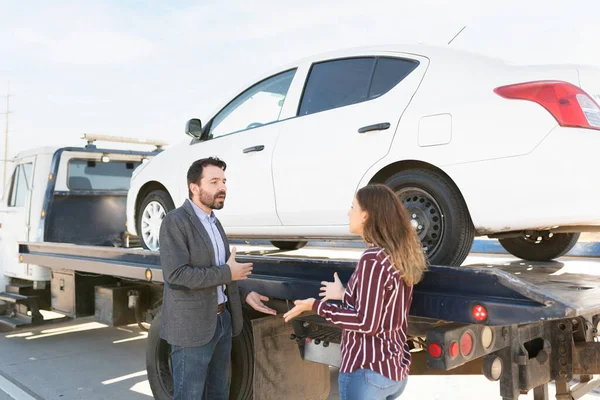 ラテン系の大人の男性と若い女性が怒りの表情で話しています 車でレッカー車の横で言い争うカップル — ストック写真