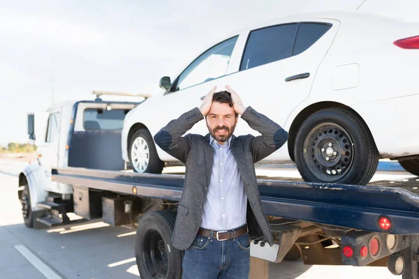 怒った表情と頭の中で手で目を合わせているラテン人 車がレッカー車に乗ってるから動揺した男 — ストック写真