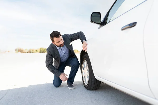 ヒスパニック系の男は平らなタイヤのために彼の車をチェック 高速道路の脇に車の問題が停まっている30代の男 — ストック写真