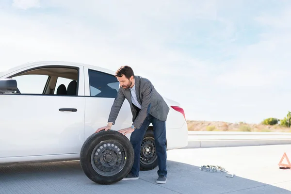 Lateinischer Mann Zieht Ersatzreifen Aus Seinem Auto Den Platten Reifen — Stockfoto