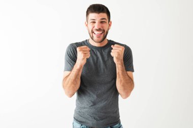 Mutlu ve neşeli bir ifadesi olan çekici bir genç adam. 20 'li yaşlardaki adam gülümsüyor ve iyi haberleri kutluyor. 