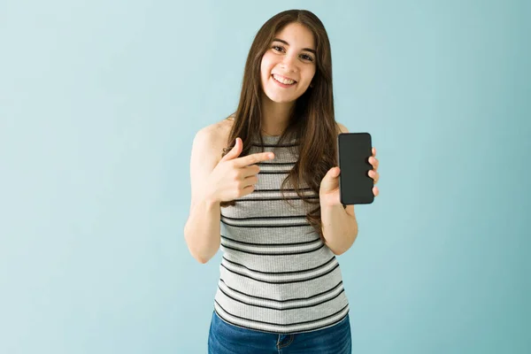 一个20多岁的快乐的高加索女人的画像 微笑着 展示着她的智能手机 指着触摸屏 — 图库照片