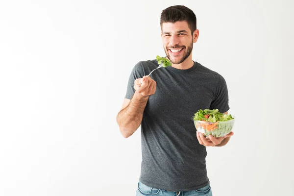 一个20多岁的有魅力 健康的男人拿着叉子和绿色沙拉吃蔬菜的画像 — 图库照片