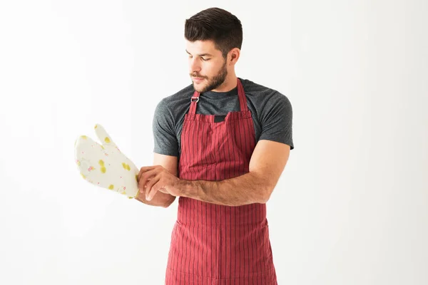 Retrato Homem Atraente Vestindo Avental Colocando Luvas Cozinha Frente Fundo — Fotografia de Stock