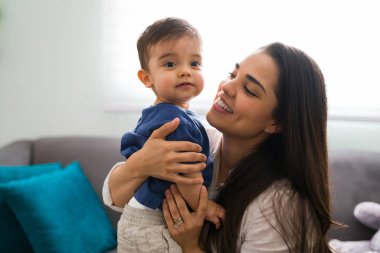 Gülümseyen genç anne ve tatlı bebeği evde.