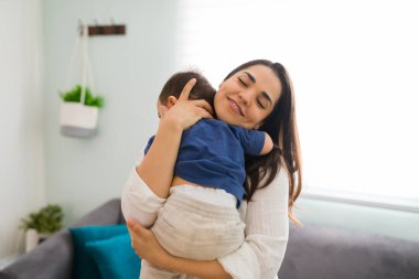 Bakımlı genç bir anne bebeğini evde taşıyıp rahatlatıyor.