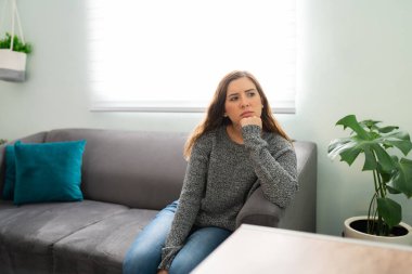20 'li yaşlarda çekici bir kadın sorunlarıyla ilgili endişeli ve stresli bir şekilde kendini kaybetti. Düşünceli ve düşünceli genç bayan salonda oturuyor.