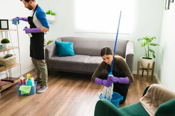 Woman Squeezing Mop Clean Floor Home While Husband Dusts Cleans — Stock Photo, Image