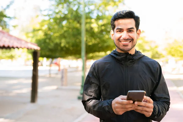 Spor Kıyafetli Genç Bir Latin Portresi Parktaki Cep Telefonunda Gülümsüyor — Stok fotoğraf