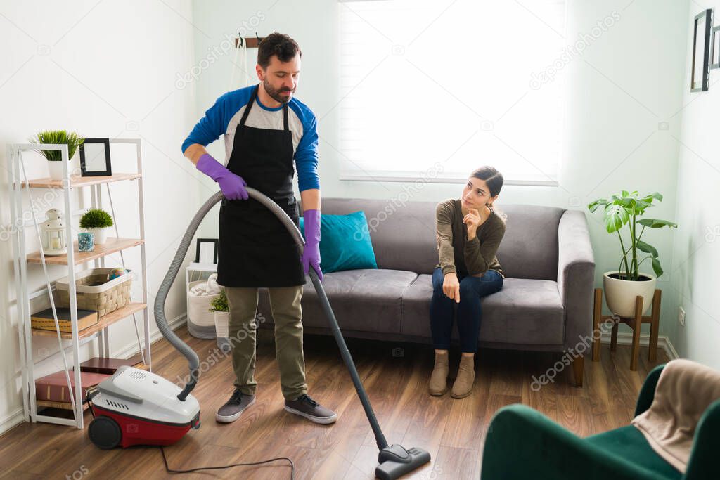 Mean woman making her partner clean the house by himself and pointing towards a dirty spot
