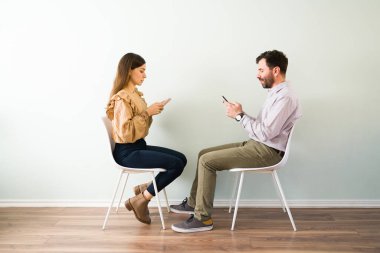 İnternet arkadaşlık sitesinde tanışan çekici bir çiftin yan görüntüsü akıllı telefonlarıyla mesajlaşıp flört ediyorlar. 