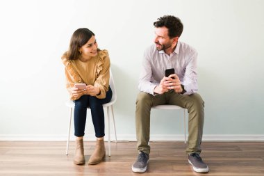 İspanyol çift internette tanışma sitesinde tanışmış. Güzel bir kadın ve yakışıklı bir adam hızlı randevu davetinde. Akıllı telefonlarını tutarken flört ediyorlar ve konuşuyorlar.