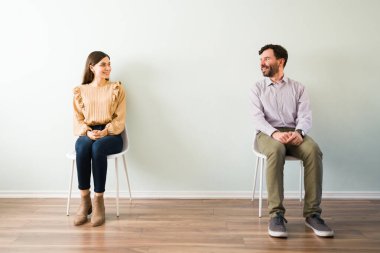 Gülümseyen ve birbirlerine bakan mutlu genç çift. Güzel bir kadın ve çekici bir erkek hızlı randevu sırasında mesafeli otururlar.