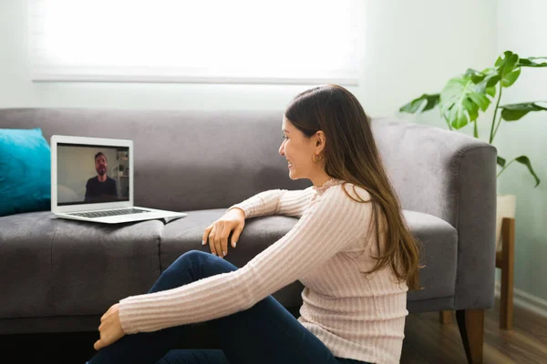 快乐的年轻女人带着笔记本电脑坐在地板上 和她的朋友在视频通话中聊天 — 图库照片