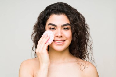 Latin bir genç kadının portresi sabah cilt bakımı için güzel ve sağlıklı cildini temizliyor. 