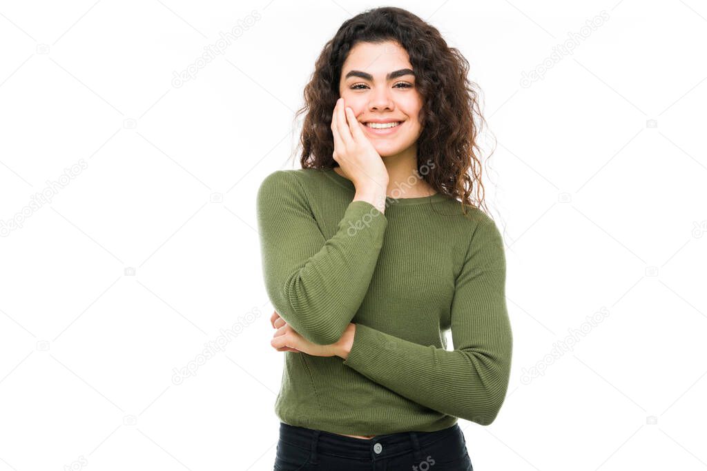 Happy latin young woman with one hand on her chin and smiling. Beautiful woman with a relaxed and peaceful expression