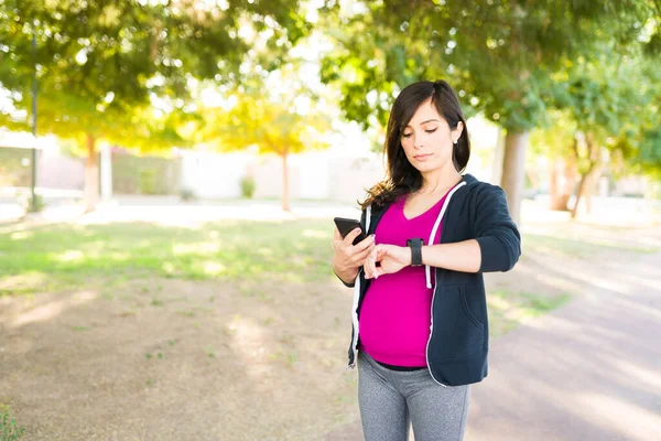 Fitte Frau Ihren Dreißigern Checkt Ihr Smartphone Und Ihre Smartwatch — Stockfoto