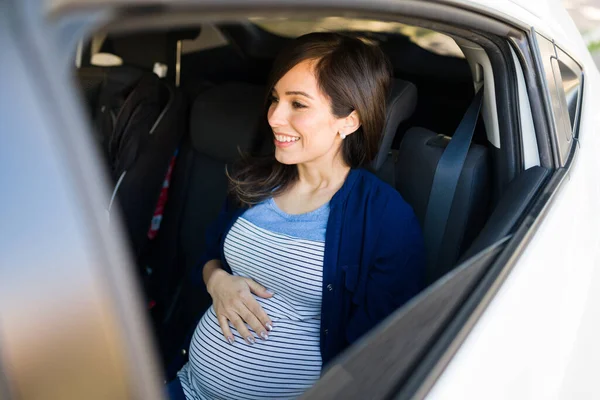 興奮した女性は赤ん坊を産むために病院に行く 赤ちゃんの車のシートの横の車の後部座席に座って幸せな妊婦 — ストック写真