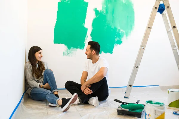 魅力的な結婚したカップル笑って 自分の部屋の壁を塗装した後 ハンサムな男と若い女性が彼らの家を改造することについて話している — ストック写真