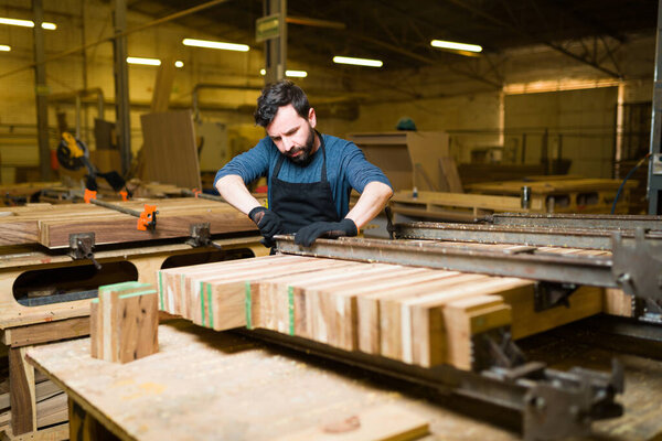 Красивый мужчина-плотник, работающий над сборкой и склеиванием кусков дерева в большой мастерской
