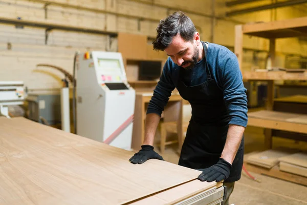 带着围裙和安全手套的专业木匠在木工车间工作 男工准备在一家木材店切胶合板 — 图库照片
