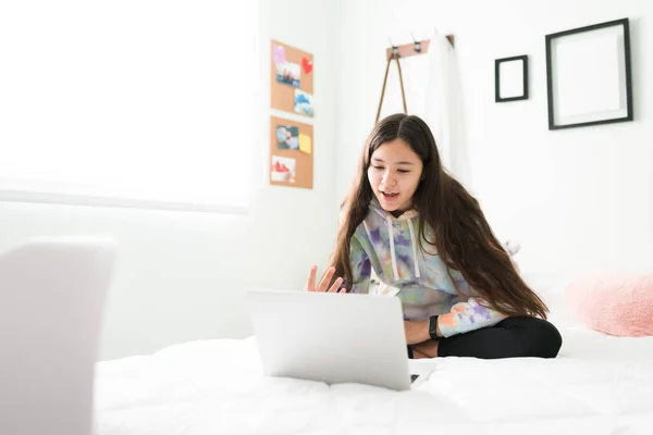 白人少女坐在床上给朋友打电话的视频 可爱的少女在笔记本电脑里和同学们视频聊天 — 图库照片