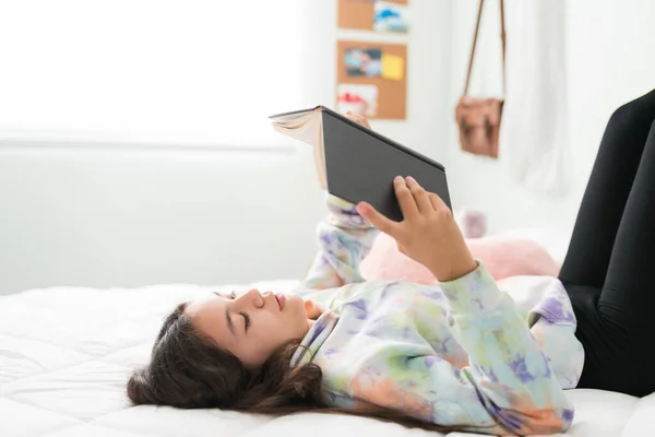 一个聪明的少女躺在床上看书的侧视图 年轻的高加索少年在卧室里享受着与小说相伴的闲暇时光 — 图库照片
