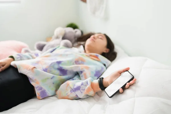 年轻的少女在床上睡着了 她用智能手机查看社交媒体 少女拿着手机睡在卧室里 — 图库照片
