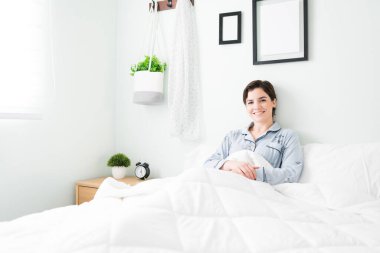 Güzel genç bir kadın sabahleyin yatakta yatarken iç çekiyor. Kafkasyalı kadın büyük, rahat yatağında dinleniyor.