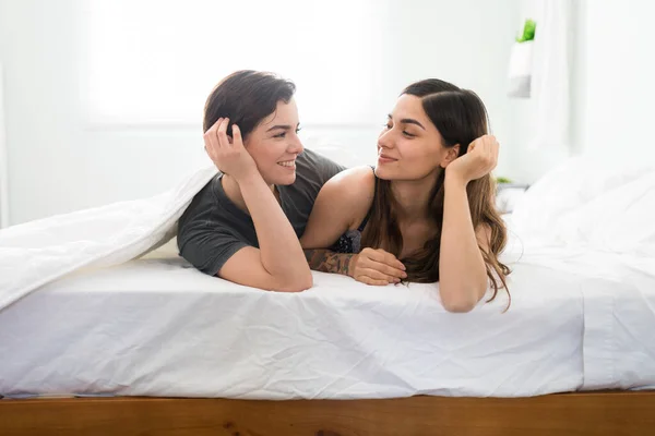 两个漂亮的女人躺在床上 面面相觑 恋爱中的年轻漂亮的女朋友们躺在卧室里 — 图库照片