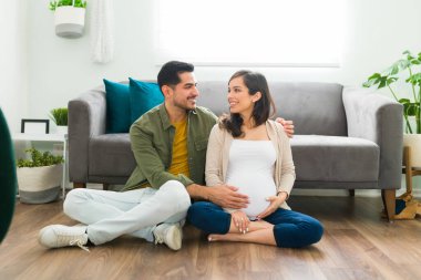 Hamile kadının karnını okşayıp sarılırken birbirlerine bakan güzel bir çift. Aşık kadın ve erkek ilk çocuklarını bekliyorlar.