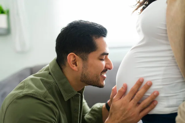 微笑的拉丁男人在他30多岁的时候正要给一个怀孕的女人的腹部一个吻 爱的夫妻为有了孩子而兴奋 — 图库照片