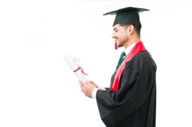 Mezuniyet törenlerinde üniversite diploması alan Latin bir gencin yandan görünüşü. Mezuniyet töreninde elinde akademik sertifikasıyla erkek mezun